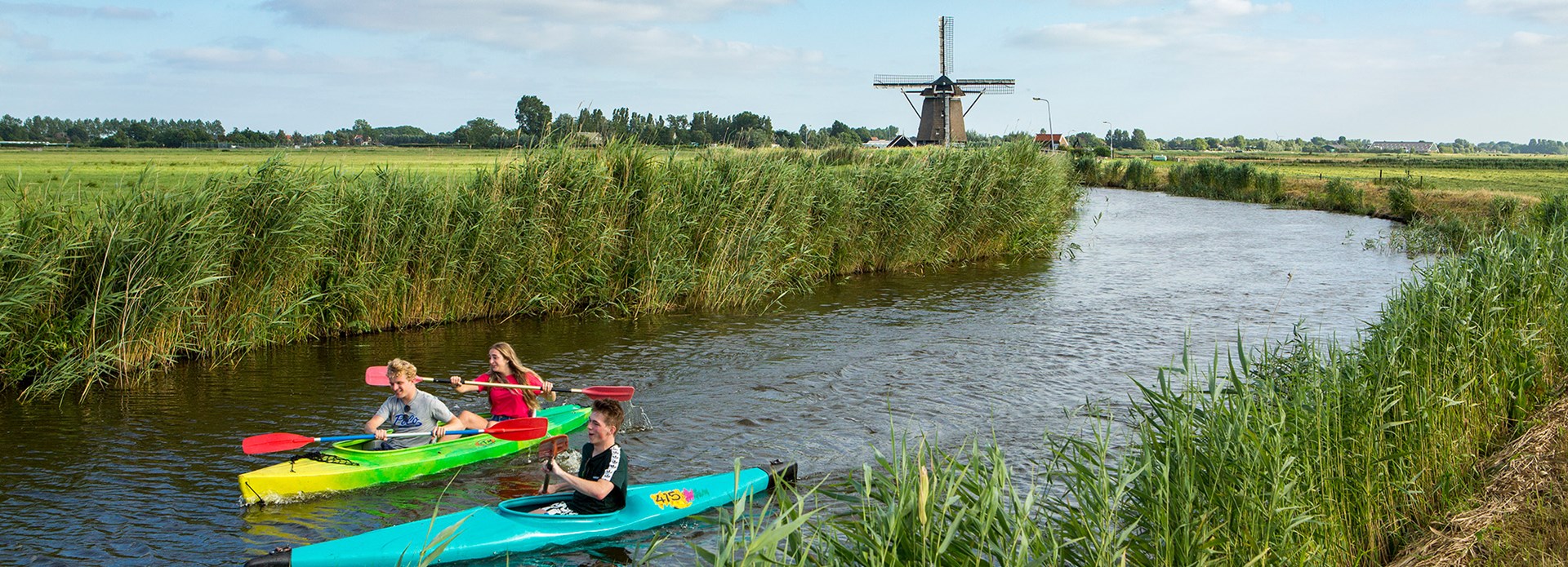 Twee mensen in een kano in Akersloot met op de achtergrond een molen